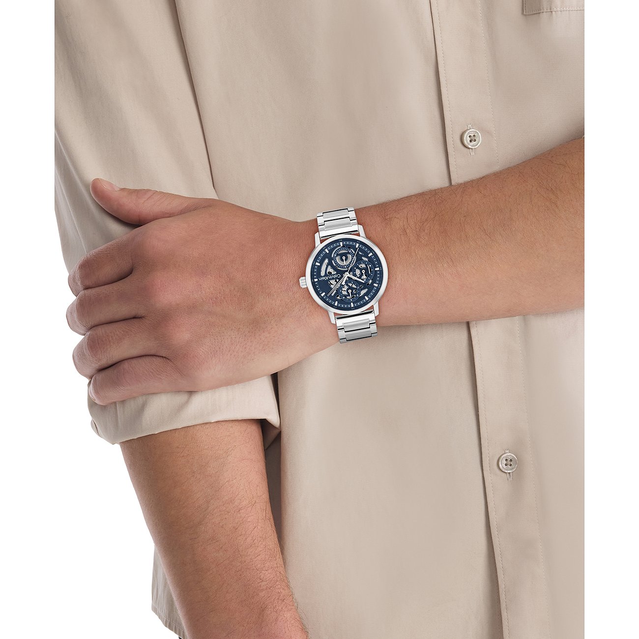Am Handgelenk eines Mannes getragene Calvin Klein Herrenuhr aus Edelstahl mit blauem Zifferblatt und silbernem Armband.