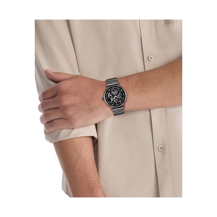 Am Handgelenk eines Mannes getragen Calvin Klein Herrenuhr aus dunkelgrauem Edelstahl mit skelettiertem Zifferblatt.
