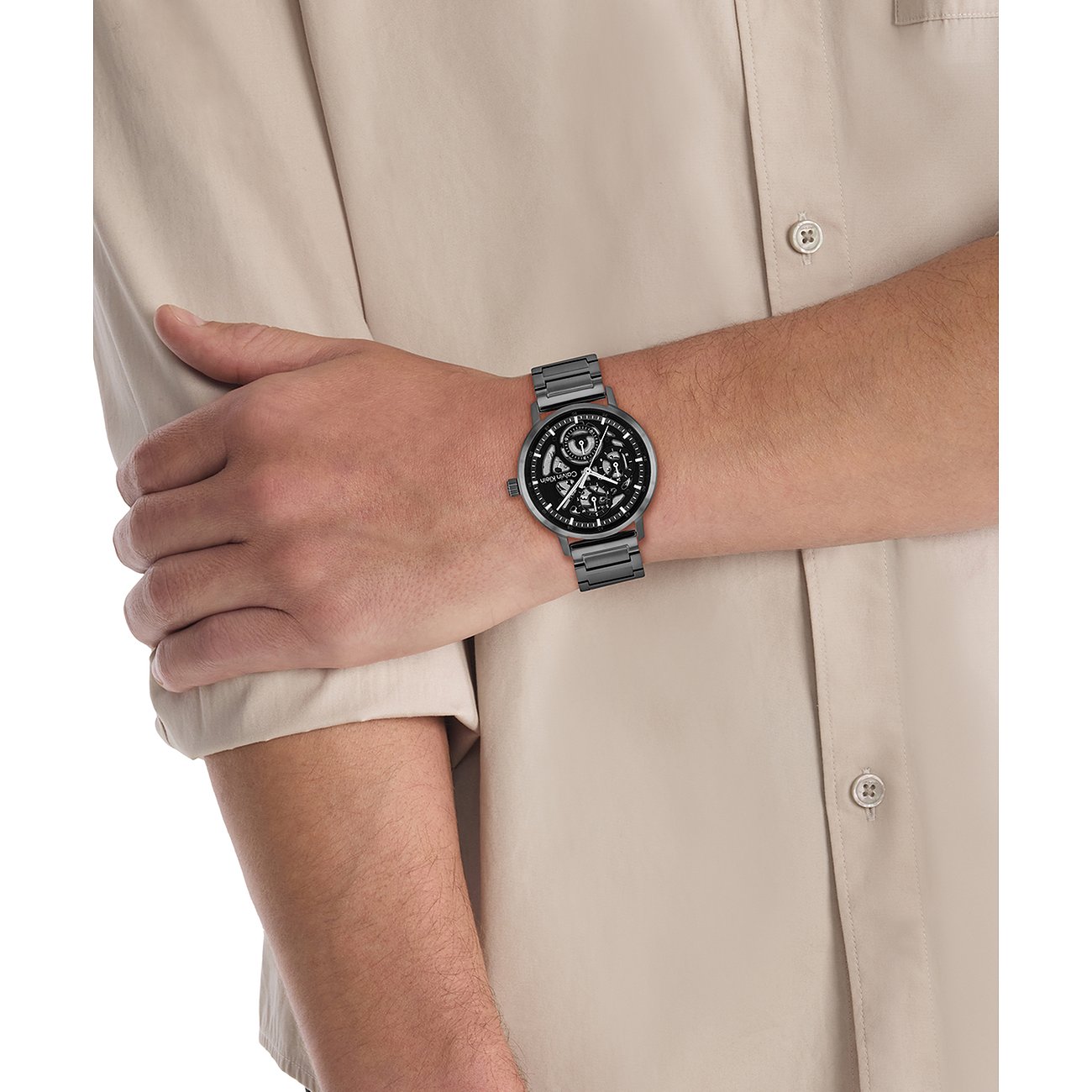Am Handgelenk eines Mannes getragen Calvin Klein Herrenuhr aus dunkelgrauem Edelstahl mit skelettiertem Zifferblatt.
