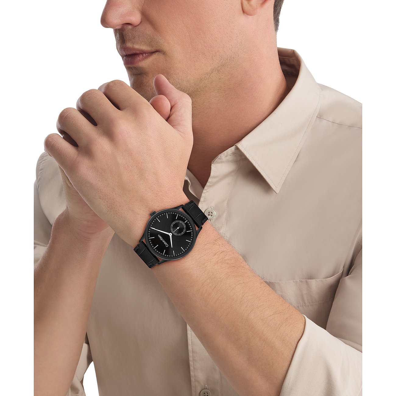 Nahaufnahme einer Calvin Klein Herrenuhr aus schwarzem Edelstahl am Handgelenk eines Mannes, der ein helles Hemd trägt.