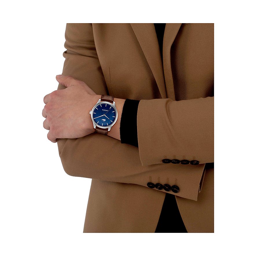 Am Handgelenk eines Mannes wird die Lacoste Herrenuhr aus Edelstahl mit braunem Armband und blauem Zifferblatt gezeigt.