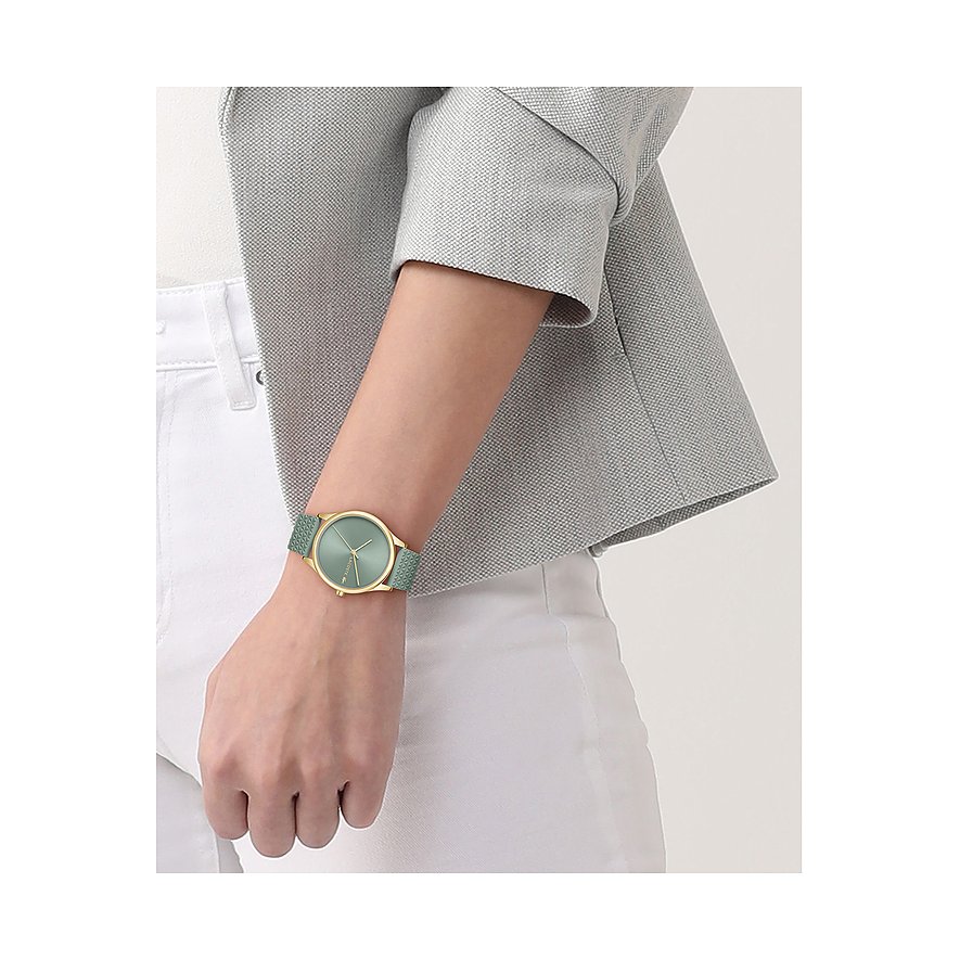 Lacoste Damenuhr aus goldfarbenem Edelstahl mit mintgrünem Zifferblatt und Armband, getragen an einem Handgelenk.