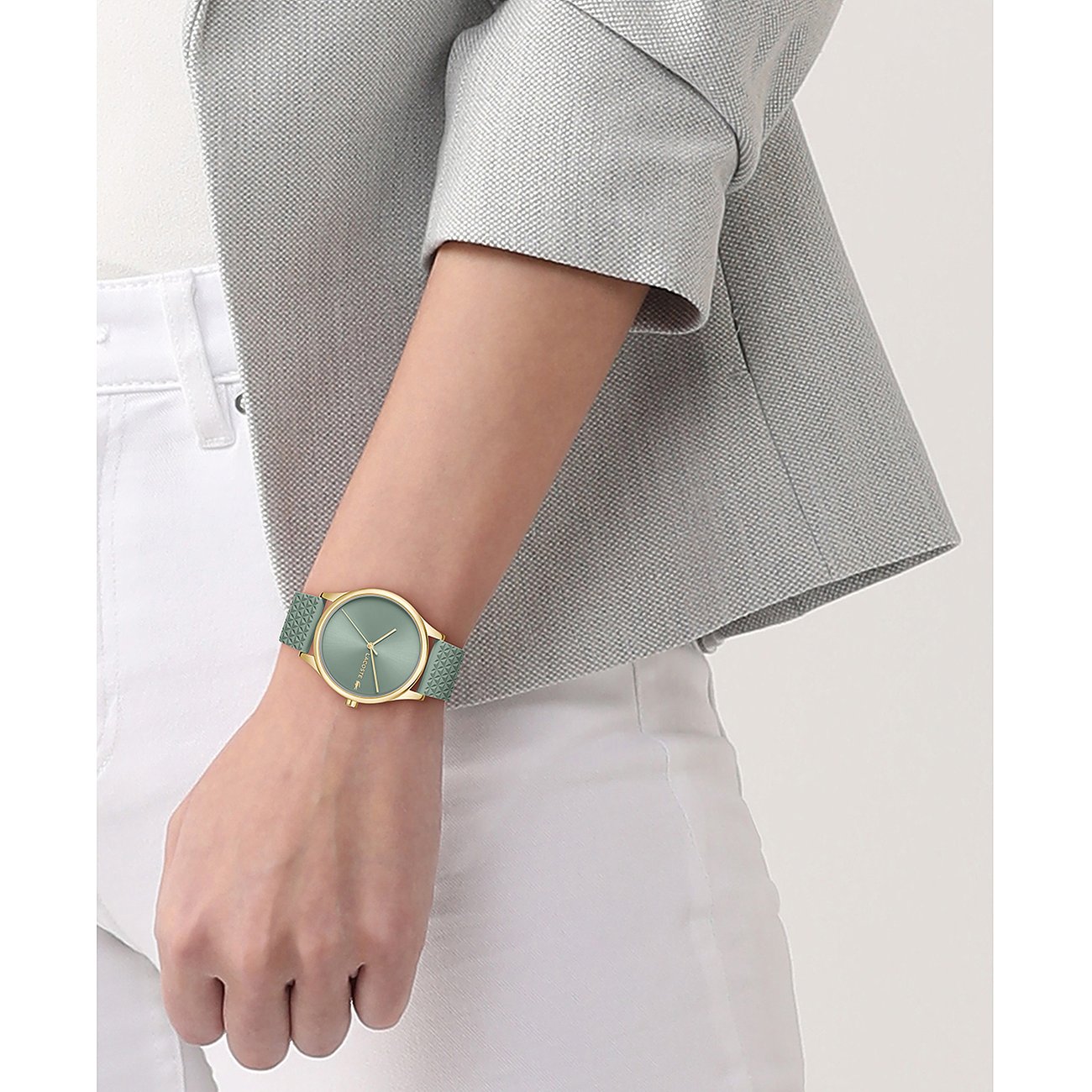 Lacoste Damenuhr aus goldfarbenem Edelstahl mit mintgrünem Zifferblatt und Armband, getragen an einem Handgelenk.