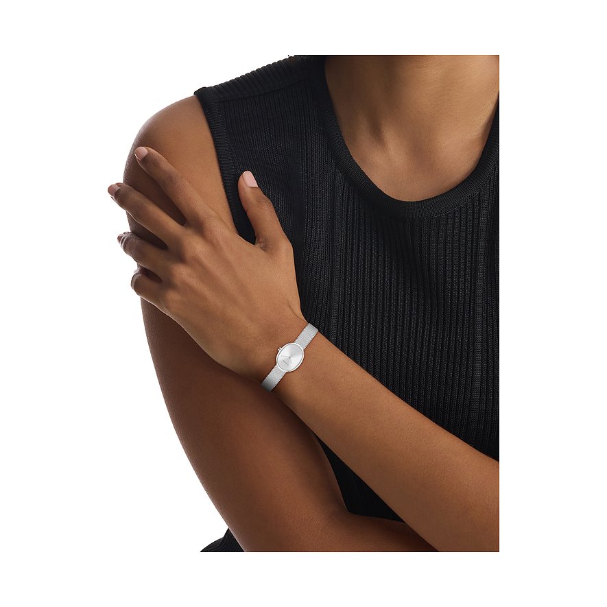 Am Arm einer Frau getragen: Calvin Klein Damenuhr aus Edelstahl mit ovalem Zifferblatt und Mesh-Armband.