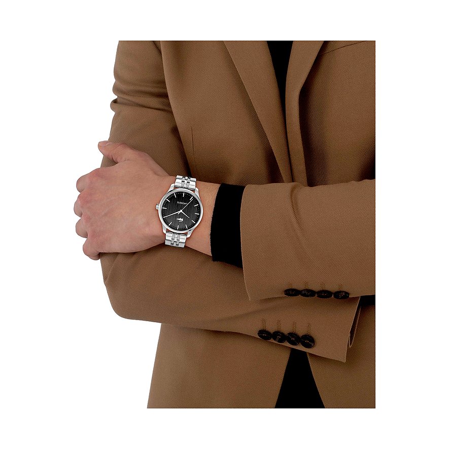 Am Handgelenk eines Mannes wird eine Lacoste Herrenuhr aus Edelstahl in Silber mit grünem Zifferblatt gezeigt.