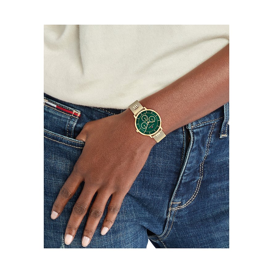 Goudkleurig Tommy Hilfiger dameshorloge van roestvrij staal met een groene wijzerplaat en fijne schakelarmband om de pols.