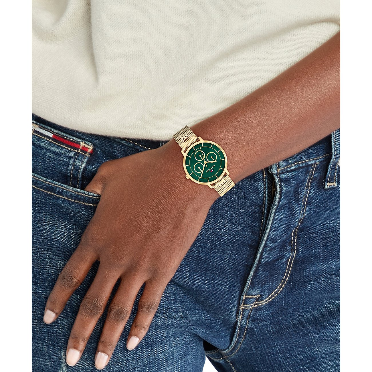 Goudkleurig Tommy Hilfiger dameshorloge van roestvrij staal met een groene wijzerplaat en fijne schakelarmband om de pols.
