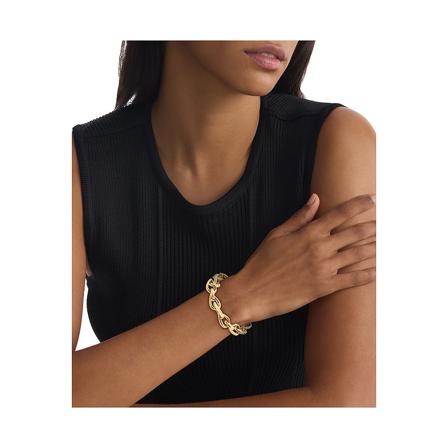 Een goudkleurige roestvrijstalen Calvin Klein armband, gedragen door een vrouw met een zwarte top.