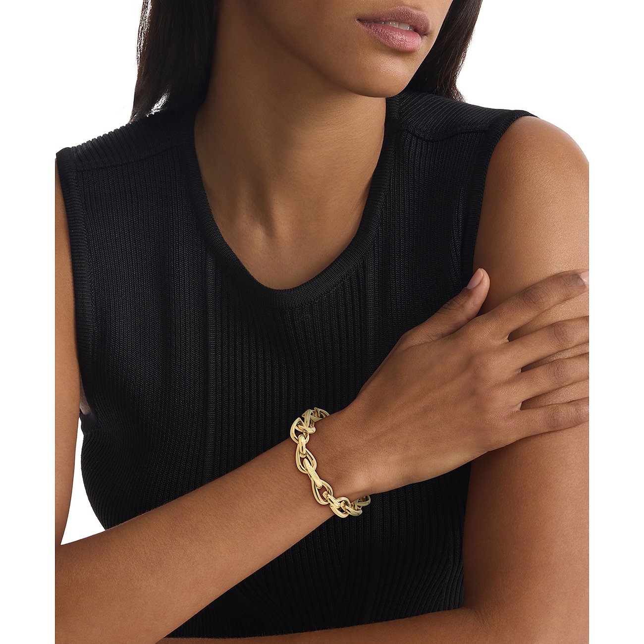 Een goudkleurige roestvrijstalen Calvin Klein armband, gedragen door een vrouw met een zwarte top.