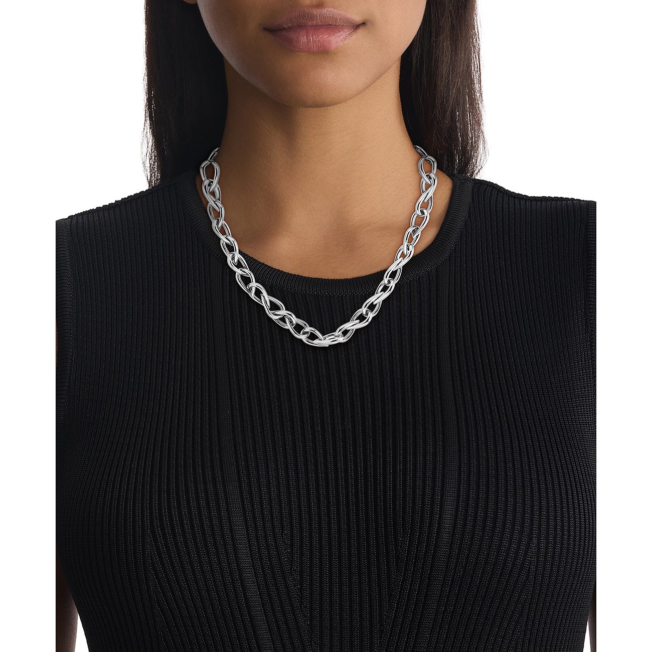 Een glanzende roestvrijstalen Calvin Klein ketting met in elkaar verstrengelde schakels. Een vrouw draagt de ketting.