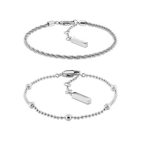 Zwei polierte Calvin Klein Armbänder aus Edelstahl auf Weiß. Eines ist eine feine Kette, das andere hat kleine Perlen.