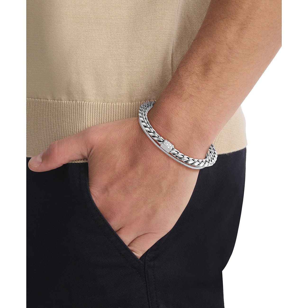 Een Calvin Klein roestvrijstalen armband, aan een pols gedragen, deels bedekt door een tas.