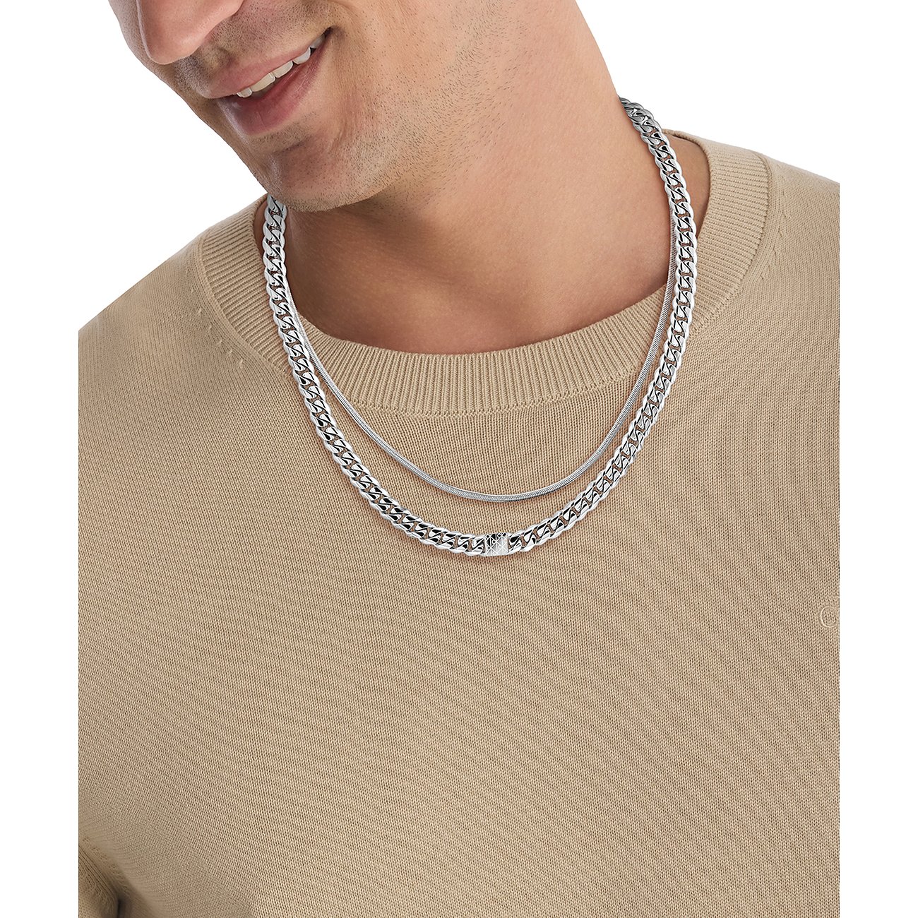 Man draagt dubbellaags Calvin Klein roestvrijstalen halsketting: een schakelketting en een figaroketting.