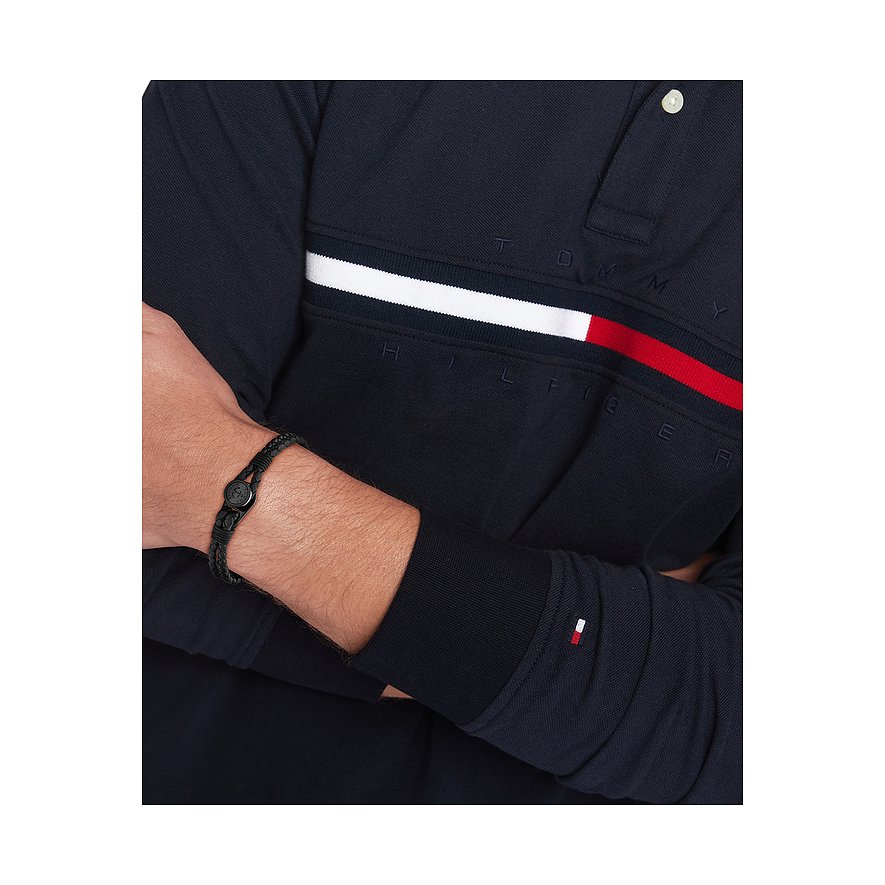 Ein Mann trägt ein Tommy Hilfiger Armband aus schwarzem geflochtenen Leder mit einem Karabinerverschluss aus Edelstahl.