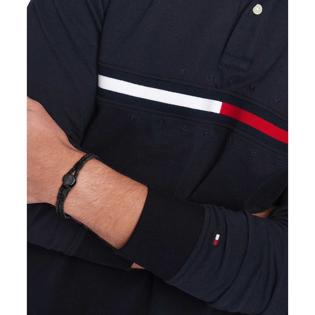 Ein Mann trägt ein Tommy Hilfiger Armband aus schwarzem geflochtenen Leder mit einem Karabinerverschluss aus Edelstahl.