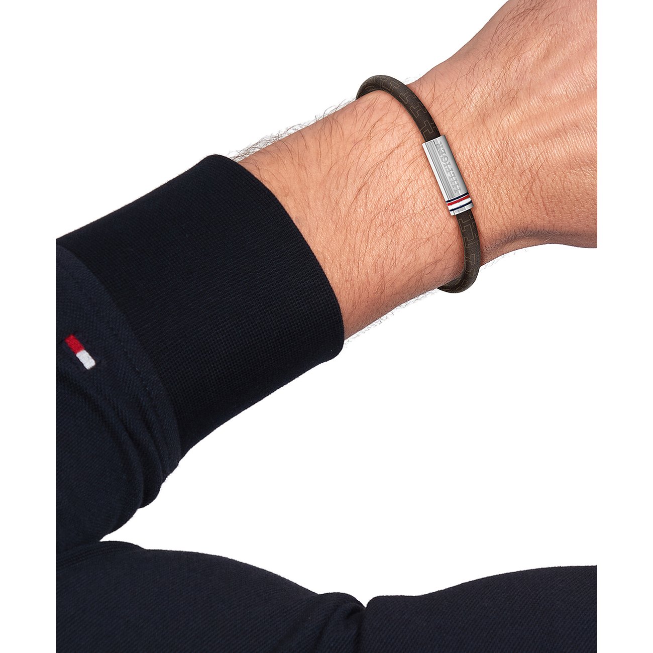 Ein Tommy Hilfiger Armband aus dunkelbraunem Leder ist am Handgelenk eines Mannes zu sehen.