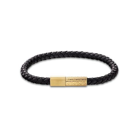 Ein Calvin Klein Armschmuck aus schwarzem, geflochtenem Leder mit einem Klickverschluss aus goldfarbenem Edelstahl.