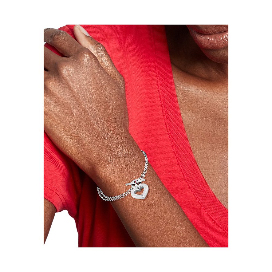 Tommy Hilfiger Armschmuck aus Edelstahl, eine silberne Gliederkette mit Herzanhänger und Knebelverschluss, auf einem Arm.