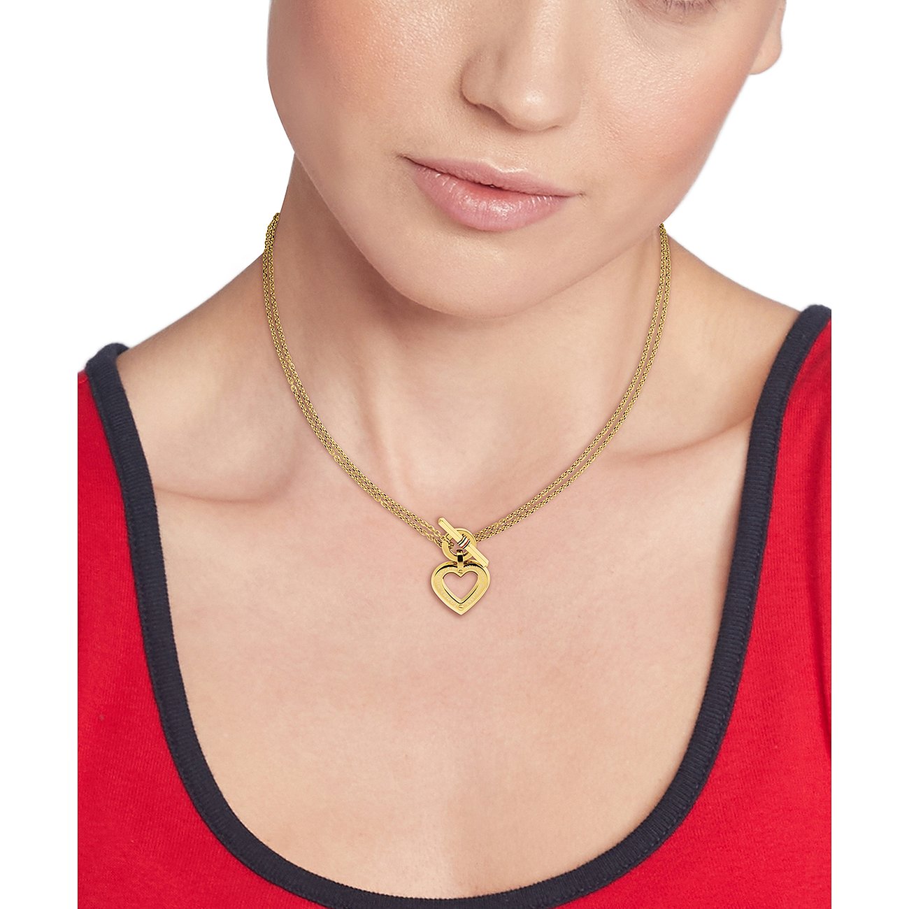 Eine Frau trägt eine Tommy Hilfiger Halskette aus goldfarbenem Edelstahl mit einem Herzanhänger.
