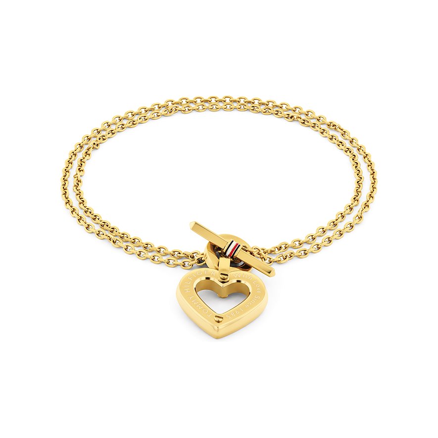 Tommy Hilfiger Armband aus goldfarbenem Edelstahl mit doppeltem Herzanhänger und Knebelverschluss auf weißem Hintergrund.