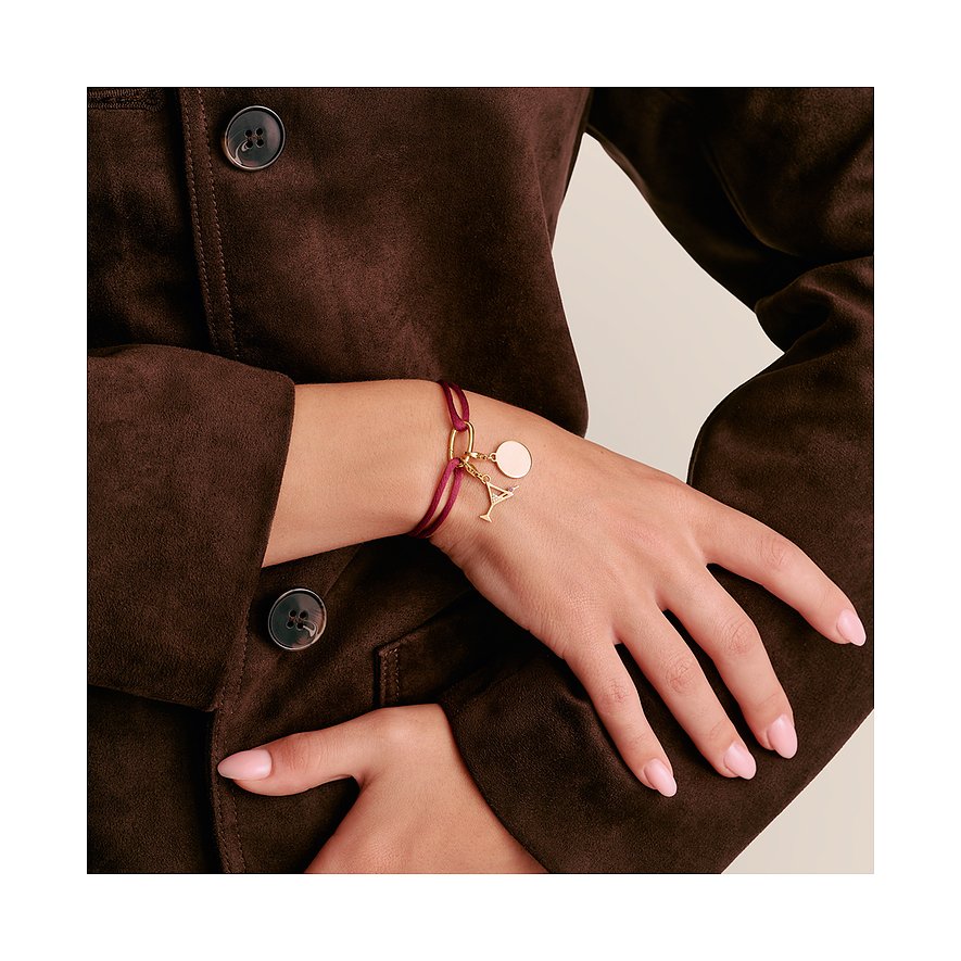 Primo piano di un bracciale Thomas Sabo in argento con nastro tessile marrone-rossastro e ciondolo a bicchiere da cocktail.