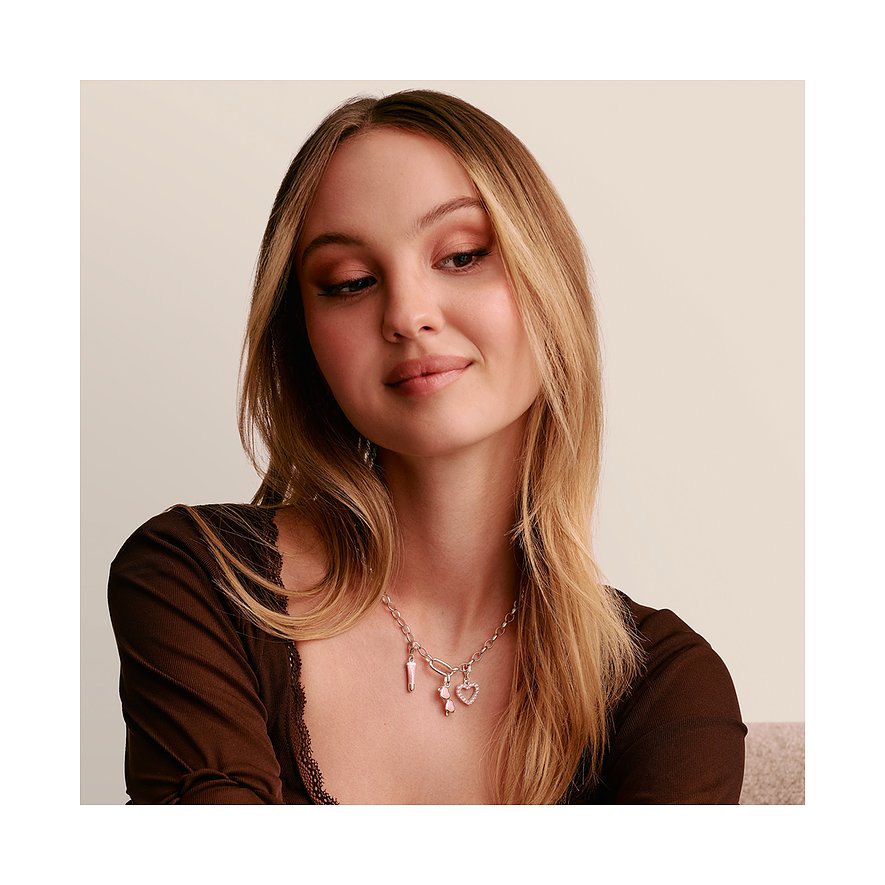 Ein Model trägt eine silberne Thomas Sabo Halskette mit Anhängern, darunter ein rosafarbenes Herz und ein Boot.