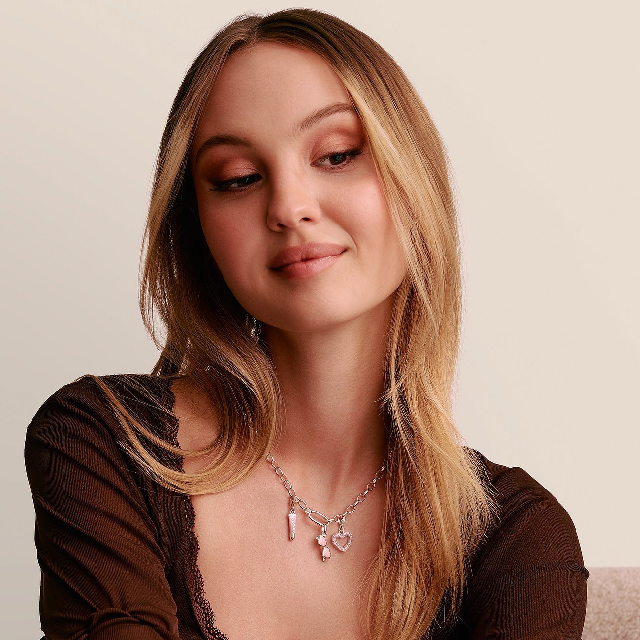Ein Model trägt eine silberne Thomas Sabo Halskette mit Anhängern, darunter ein rosafarbenes Herz und ein Boot.