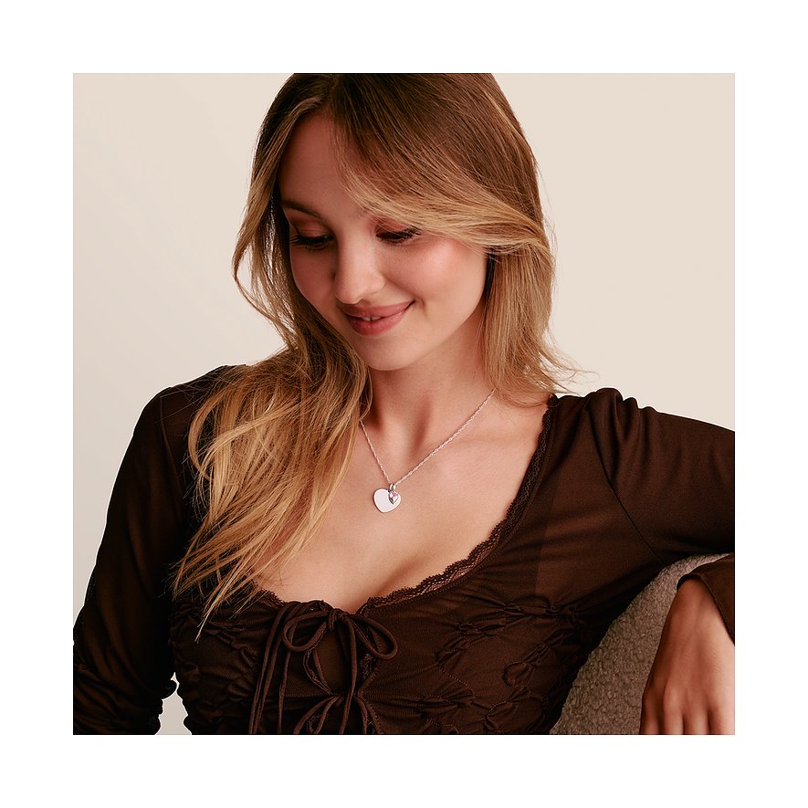 Una donna indossa una collana Thomas Sabo in argento con un pendente a forma di cuore e uno zircone rosa.