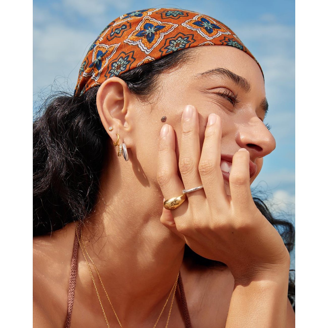 Mannequin portant des boucles d'oreilles Ania Haie en argent 925 avec zircons. Vue latérale du visage souriant.