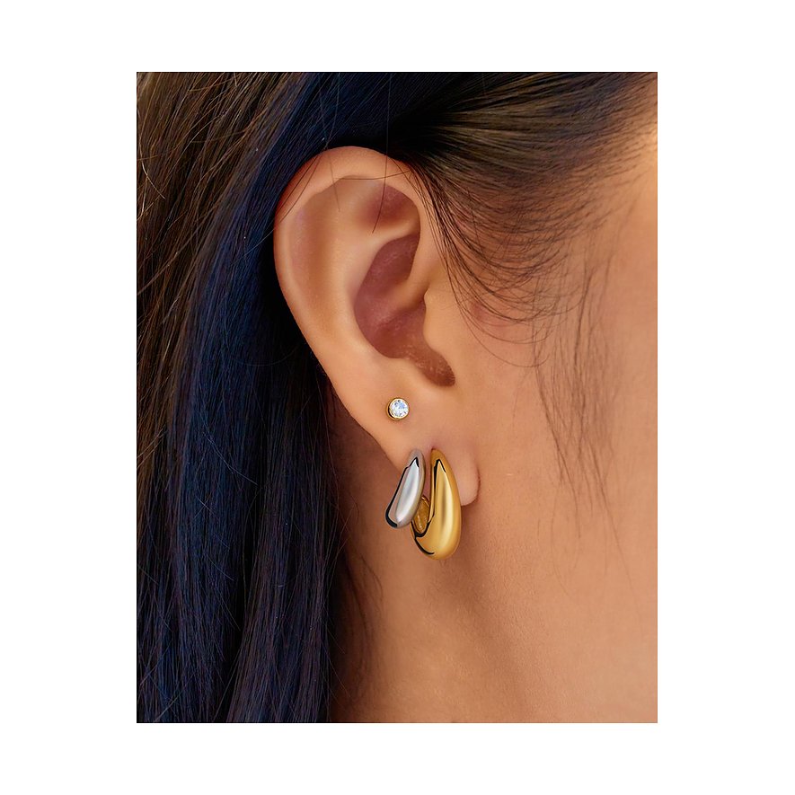 Nahaufnahme eines Ohres, das zwei Ania Haie Ohrringe trägt: einen goldenen Ohrring und einen silbernen Ohrring.