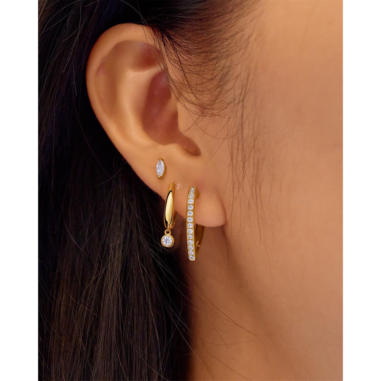 Drei Ania Haie Ohrringe aus vergoldetem Silber mit Zirkonia-Farbsteinen an einem Ohr getragen.