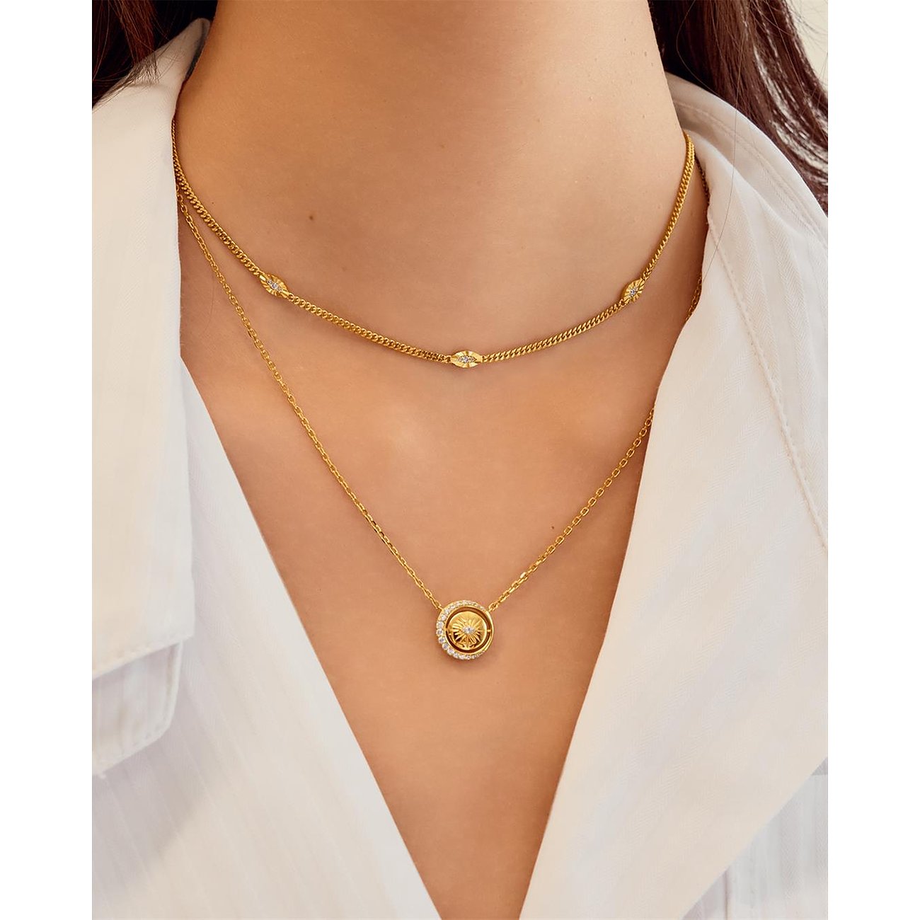 Vrouw draagt twee Ania Haie kettingen: een gouden choker en een gouden ketting met ronde zirkonia hanger.
