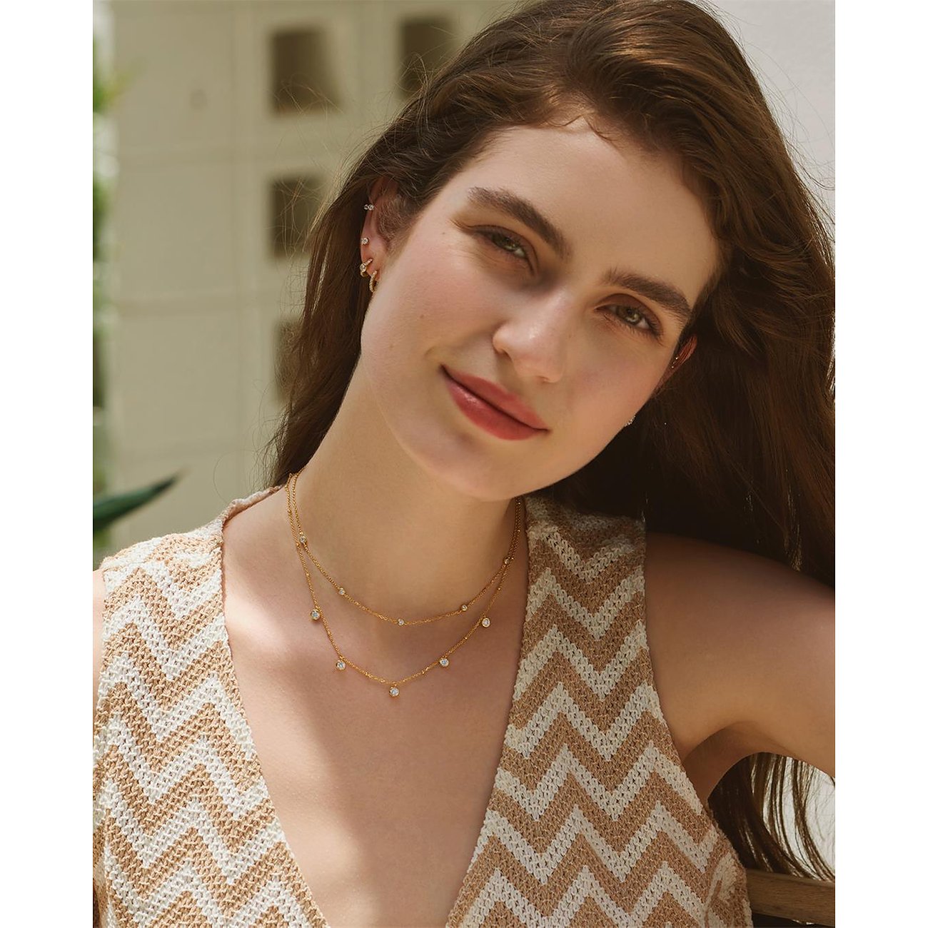 Een model draagt een glanzend gouden, dubbele Ania Haie zilveren halsketting met gekleurde zirkoniasteentjes.