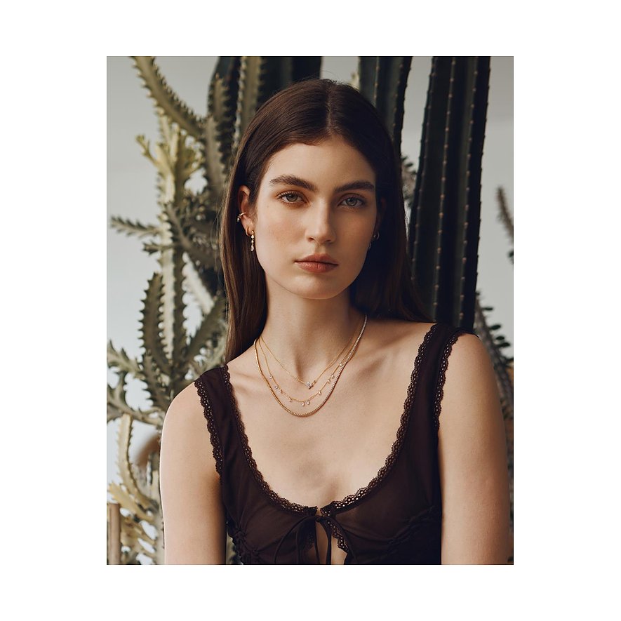 Close-up van een vrouw met drie verfijnde, gelaagde Ania Haie 925 zilveren kettingen met zirkonia.