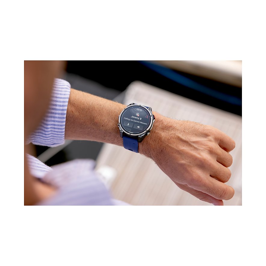 Eine Garmin Smartwatch aus Metall mit dunkelblauem Armband und beleuchtetem Zifferblatt am Handgelenk eines Mannes.