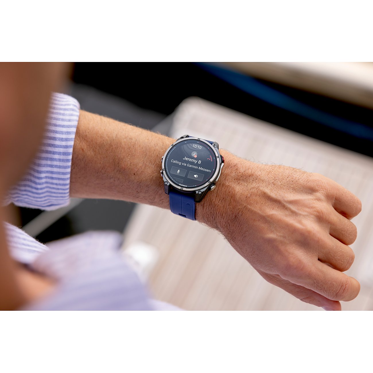 Eine Garmin Smartwatch aus Metall mit dunkelblauem Armband und beleuchtetem Zifferblatt am Handgelenk eines Mannes.