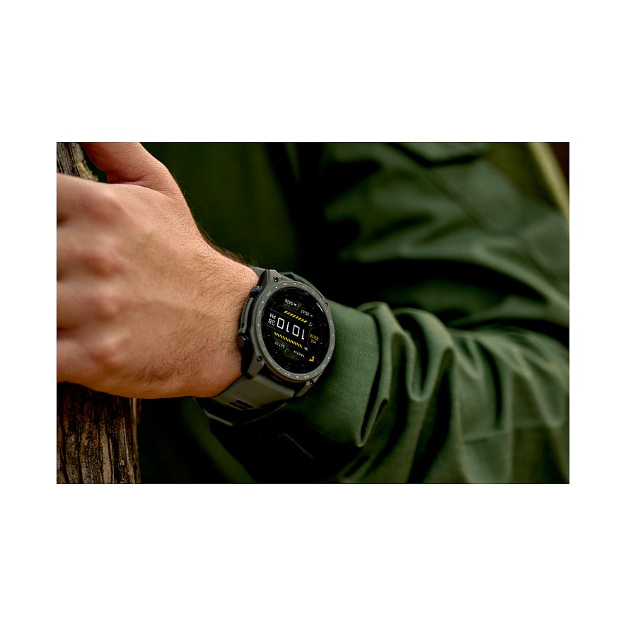 Nahaufnahme einer Garmin Smartwatch aus Titan am Handgelenk eines Mannes, der auf einem Baumstamm ruht.