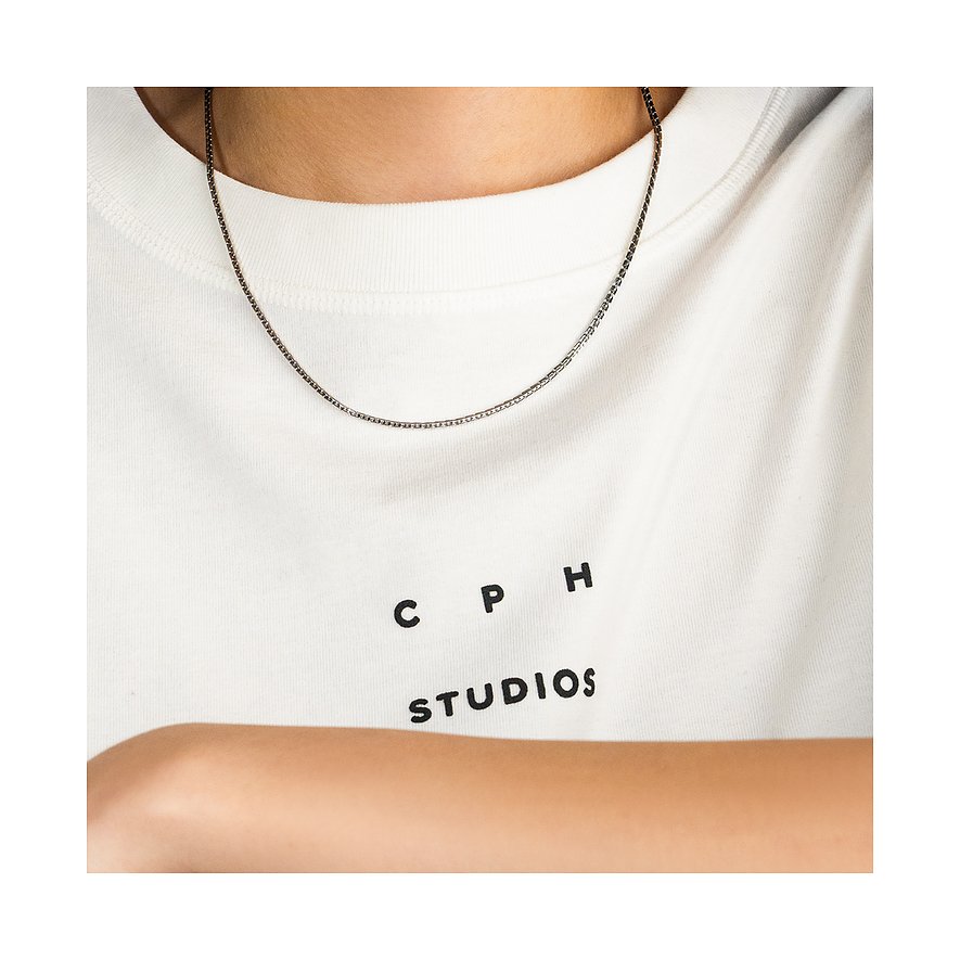 Eine graue Kette aus Edelstahl von Copenhagen Studios liegt auf einem weißen T-Shirt mit dem Aufdruck 