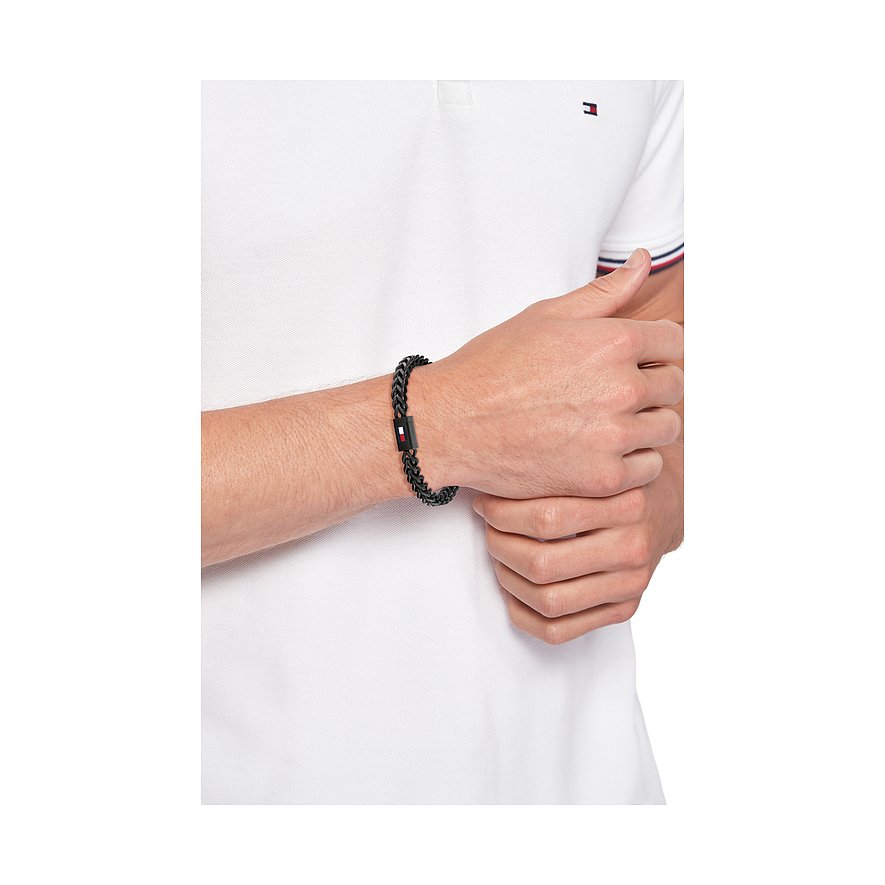 Ein von Tommy Hilfiger entworfenes Armband aus schwarzem Edelstahl, das am Handgelenk eines Mannes zu sehen ist.