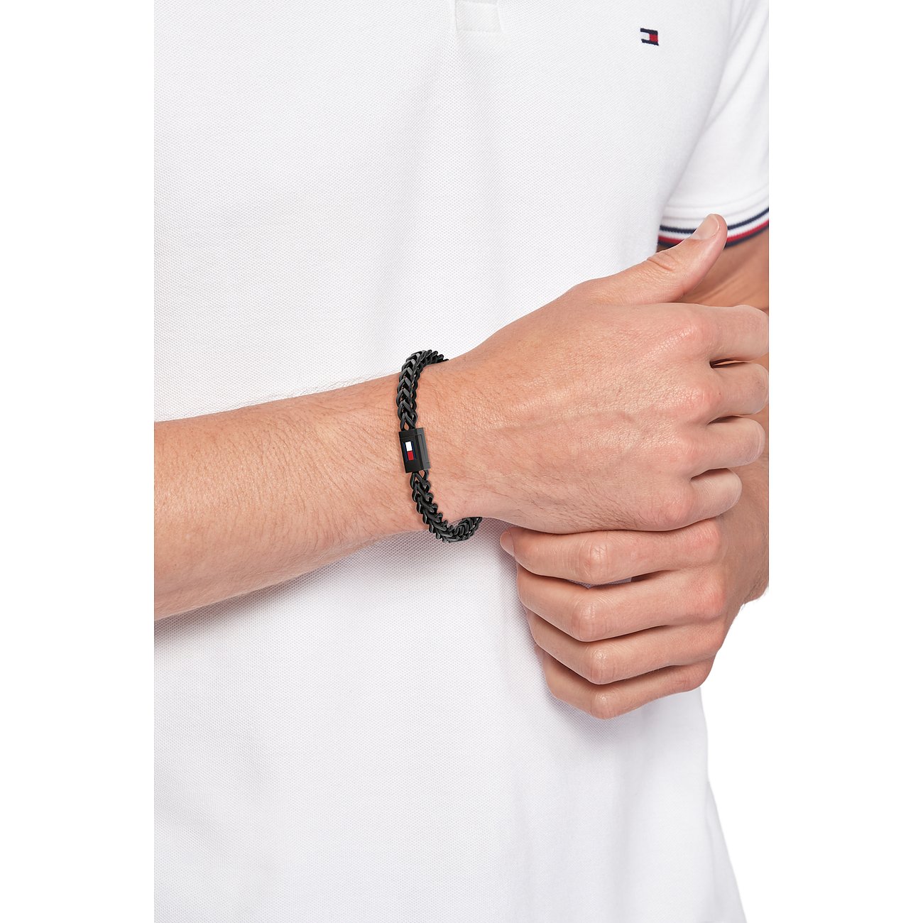 Ein von Tommy Hilfiger entworfenes Armband aus schwarzem Edelstahl, das am Handgelenk eines Mannes zu sehen ist.