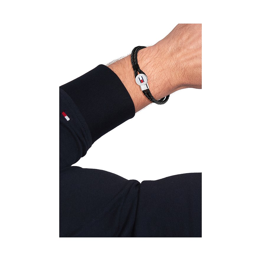Een Tommy Hilfiger zwart leren armband met gepolijste roestvrijstalen sluiting, gedragen om een mannenpols.