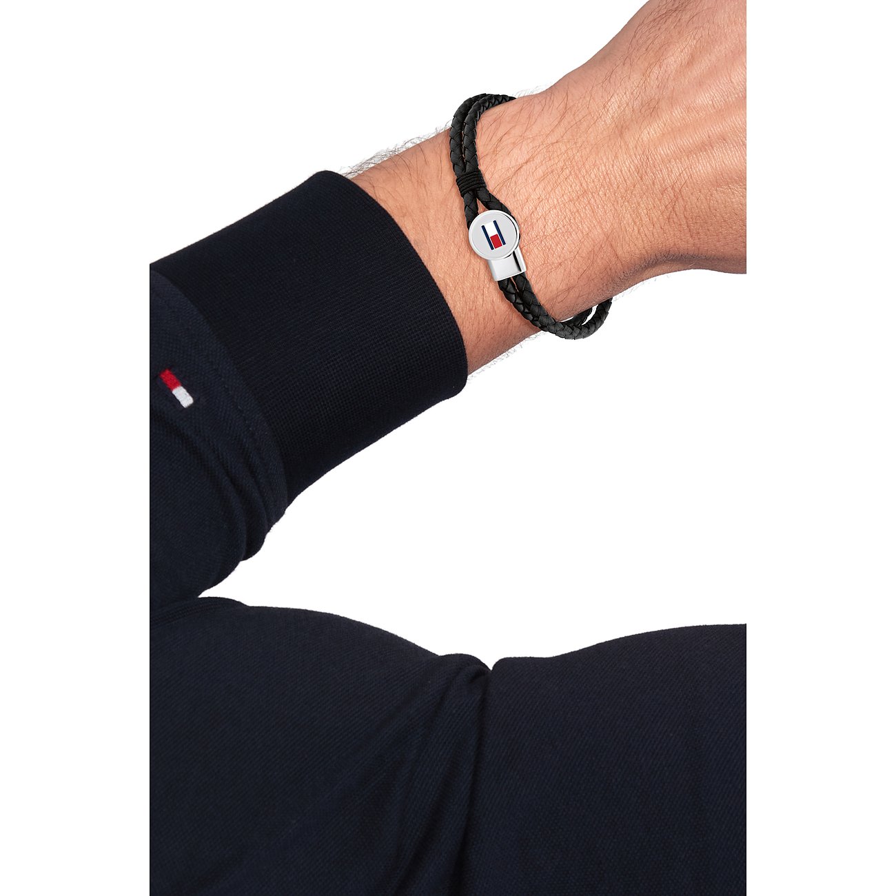 Een Tommy Hilfiger zwart leren armband met gepolijste roestvrijstalen sluiting, gedragen om een mannenpols.