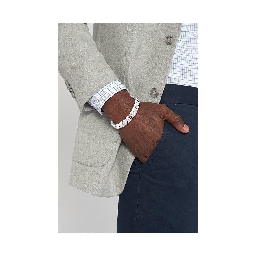 Am Handgelenk eines Mannes sitzt ein weißes Tommy Hilfiger Armband aus Edelstahl mit rotem, weißem und blauem Streifen.