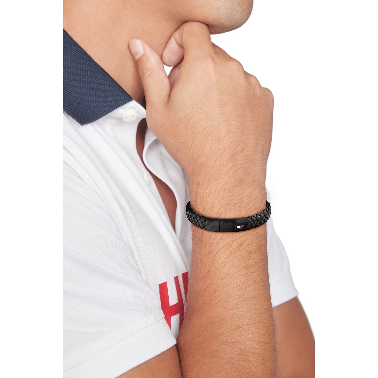 Ein Mann trägt ein geflochtenes Tommy Hilfiger Lederarmband mit einem Verschluss aus Edelstahl am Handgelenk.