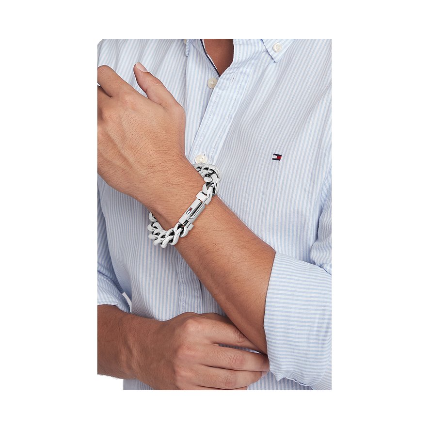Am Handgelenk eines Mannes ein Tommy Hilfiger Armschmuck aus weißem und schwarzem Edelstahl, der sich ineinander verschlingt.