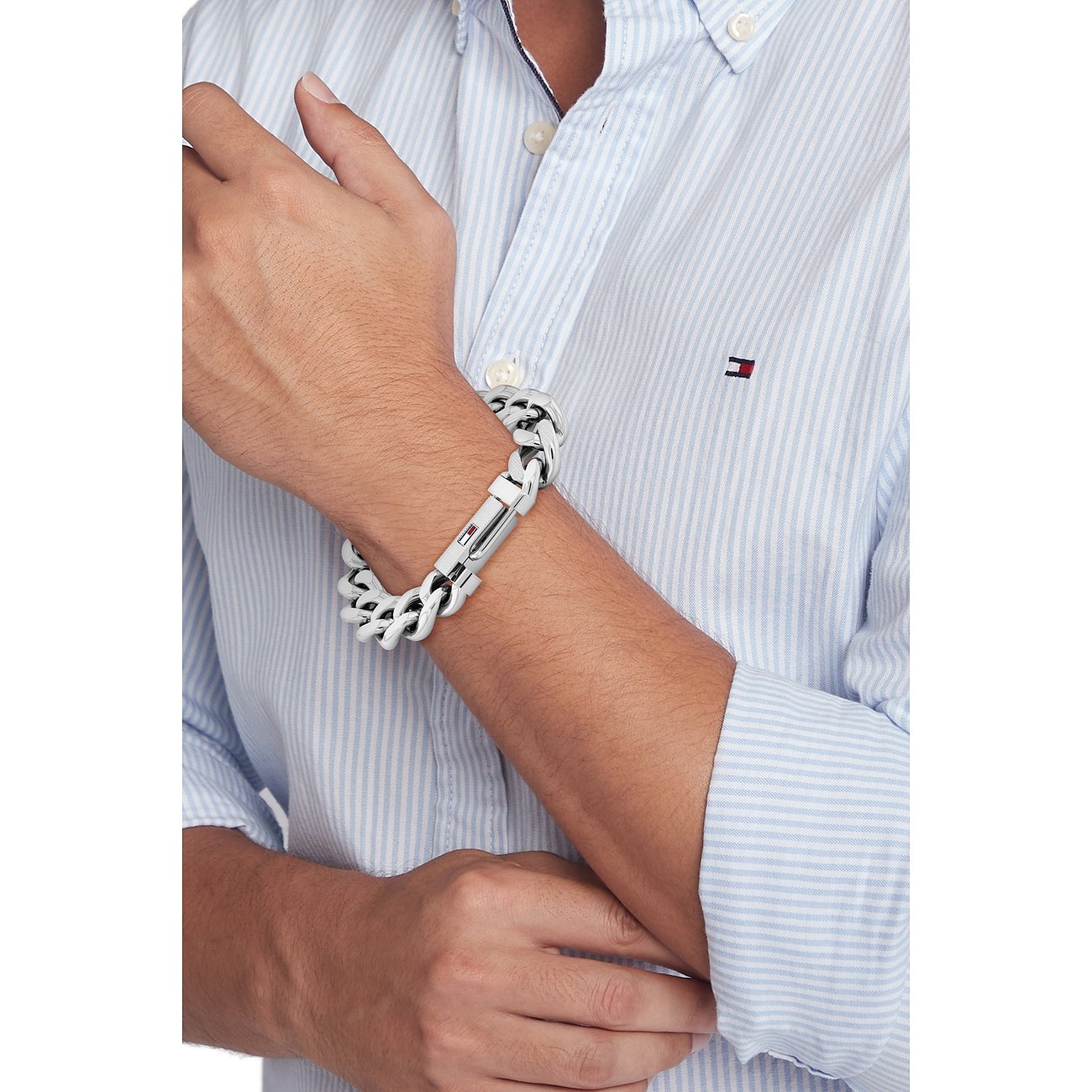 Am Handgelenk eines Mannes ein Tommy Hilfiger Armschmuck aus weißem und schwarzem Edelstahl, der sich ineinander verschlingt.