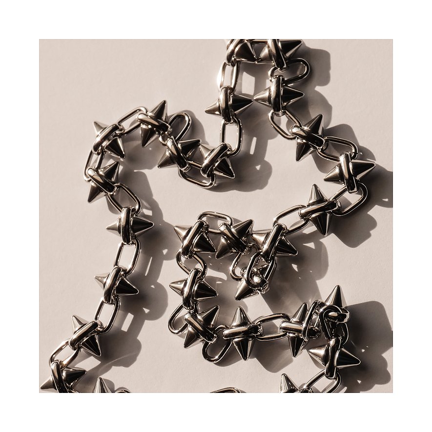 Close-up van een Liebeskind stoeprandketting van roestvrij staal met regelmatige, puntige, conische studs.