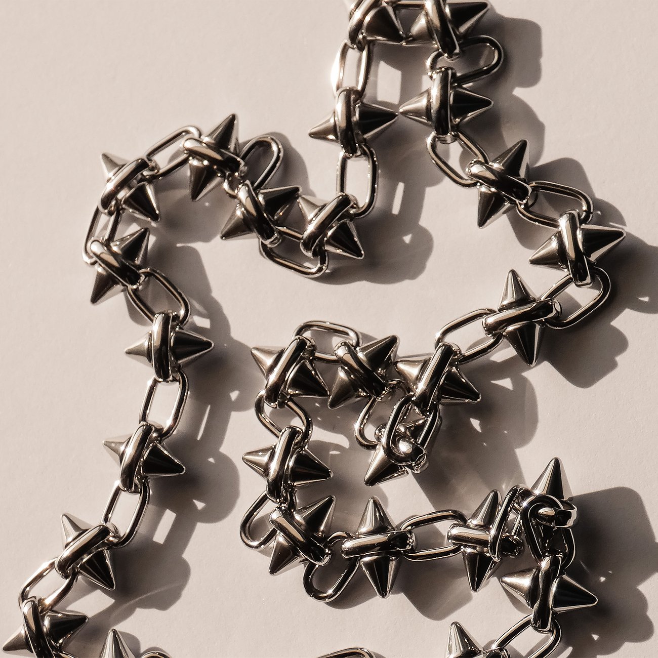Close-up van een Liebeskind stoeprandketting van roestvrij staal met regelmatige, puntige, conische studs.