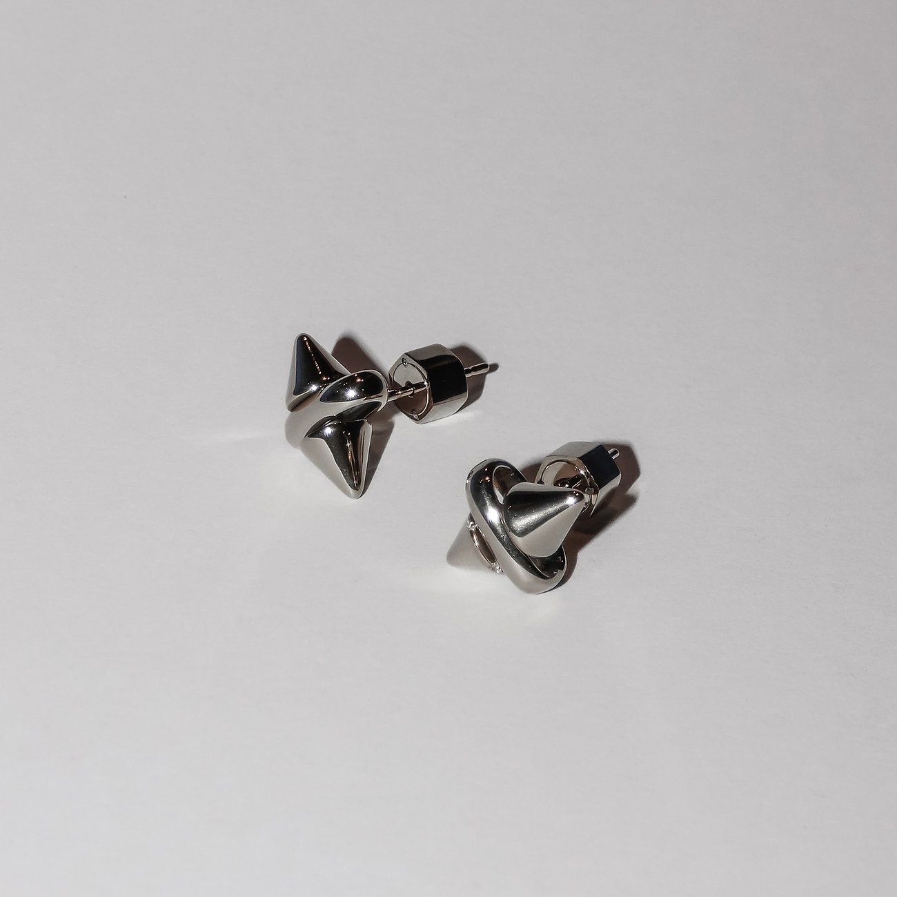 Zwei moderne Liebeskind Ohrstecker aus glänzendem Edelstahl, die spitz zulaufende, geometrische Formen zeigen.