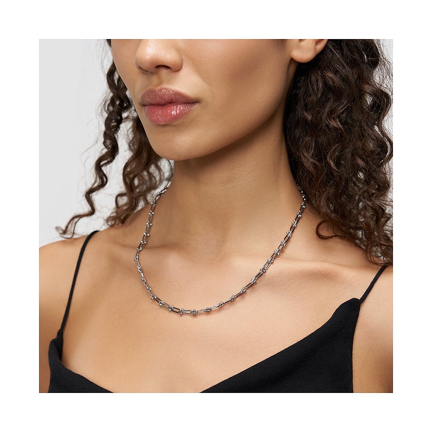 Gros plan d'une femme portant le collier Liebeskind brillant en maillons d'acier inoxydable oblongs et ronds.